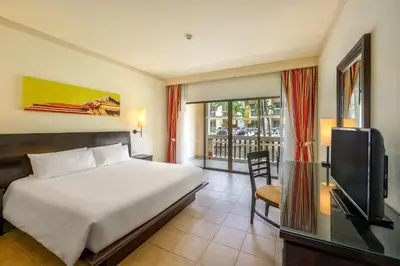 a bedroom with a bed and a tv and a window at Centara Kata Resort Phuket in Kata Beach