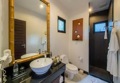 a bathroom with a sink and a toilet and a mirror at The Bell Pool Villa Resort Phuket in Kamala Beach
