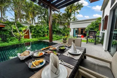 a table with food on it next to a pool at The Bell Pool Villa Resort Phuket in Kamala Beach