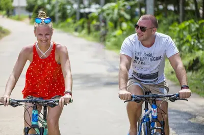 a man and a woman riding bikes down a road at Barcelo Coconut Island, Phuket in Phuket Town