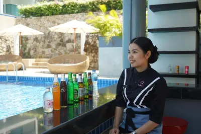 a woman standing in front of a bar with drinks at Sugar Palm Grand Hillside - SHA Plus in Kata Beach