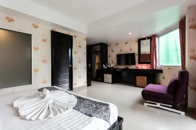 a bedroom with a bed and a purple chair at 7Q Patong Beach Hotel in Patong Beach