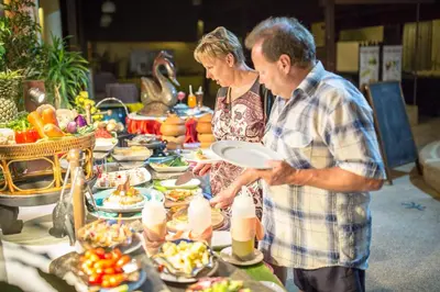 a man and woman standing in front of a buffet of food at Karona Resort & Spa - SHA Extra Plus in Karon Beach