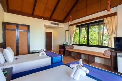 a hotel room with two beds and a television at Karona Resort & Spa - SHA Extra Plus in Karon Beach