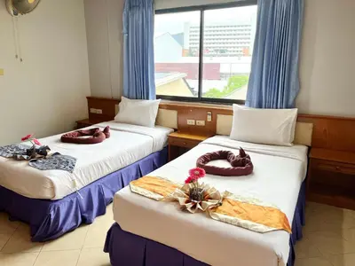 two beds in a room with a window at Patong Lamai Residence in Patong Beach