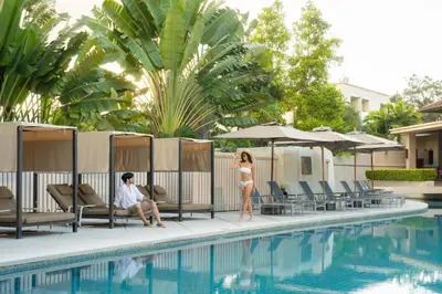 a man and a woman standing next to a swimming pool at Dewa Phuket Resort & Villas, Nai Yang Beach in Nai Yang Beach