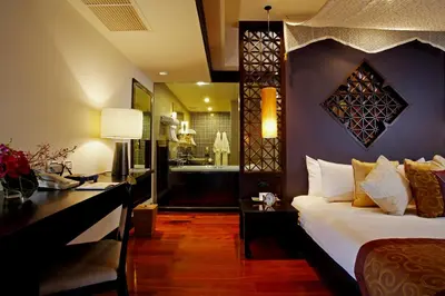 a bedroom with a bed and a desk and a bathroom at Dusit Thani Laguna Phuket in Bang Tao Beach