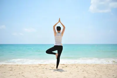 a woman is doing yoga on the beach at Dusit Thani Laguna Phuket in Bang Tao Beach