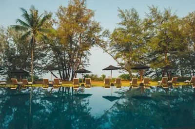 a swimming pool with lounge chairs and umbrellas at SALA Phuket Mai Khao Beach Resort in Mai Khao Beach