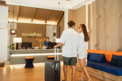 a man and woman standing in a hotel lobby with a suitcase at Villa Zolitude Resort & Spa - SHA Extra Plus in Chalong