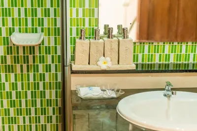 a bathroom with a sink and green tiled walls at Phi Phi Anita Resort in Phi Phi Don