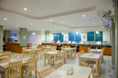 a restaurant with tables and chairs and a cafeteria at Baumancasa Beach Resort in Karon Beach