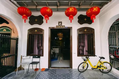 a yellow bike parked in front of a building with red lanterns at Aekkeko hostel in Phuket Town