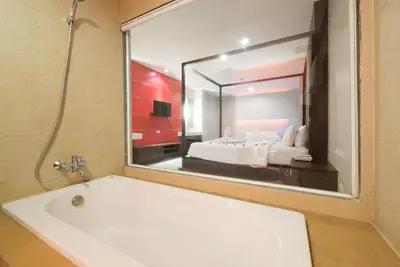 a bathroom with a bath tub and a large mirror at Alfresco Phuket Hotel in Patong Beach