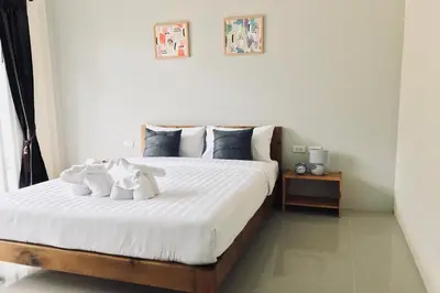a bedroom with a large bed with white sheets at Snooze Inn Phuket - Free Shuttle to Bang Rong Pier in Ban Pa Khlok