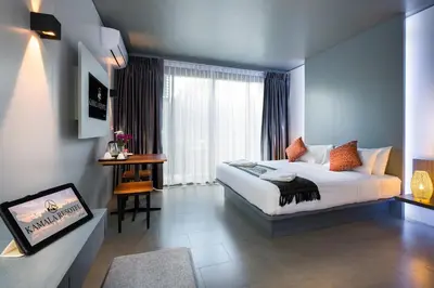a bedroom with a bed and a large window at Kamala Resotel, SHA Extra Plus in Kamala Beach