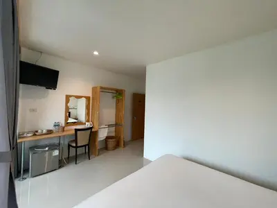 a room with a bed and a desk with a mirror at Dwell Phuket Airport Hotel at Naiyang in Nai Yang Beach