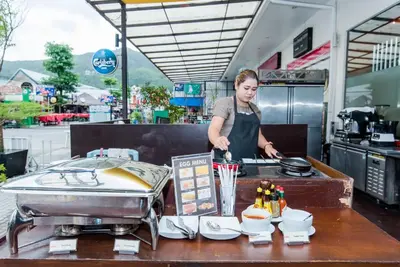 a woman standing in a kitchen preparing food at ASHLEE Hub Hotel Patong in Patong Beach