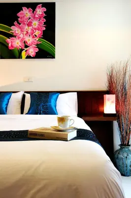 a bed with a book and a cup on top of it at Ruen Buathong Boutique Hotel Patong Beach in Patong Beach