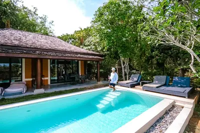 a person standing by a swimming pool next to a house at Bungalow VILLA Cha Cha in Ko Yao Noi