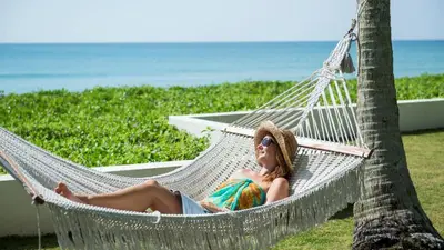 a woman laying in a hammock on the beach at Jivana Beach Villas in Natai Beach