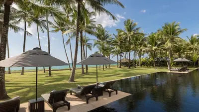 a resort pool with chairs and umbrellas and palm trees at Jivana Beach Villas in Natai Beach