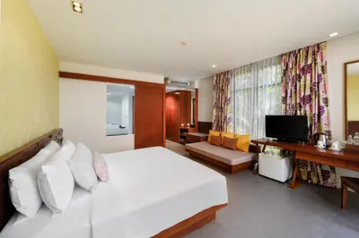 a bedroom with a white bed and a television at Karon Phunaka Resort in Karon Beach