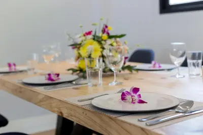 a table with plates and glasses and a flower on it at Kamala Beach House - 1 min walk to beach in Kamala Beach