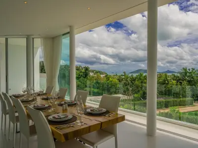 a dining room with a table and chairs and a large window at Villa Abiente in Thalang