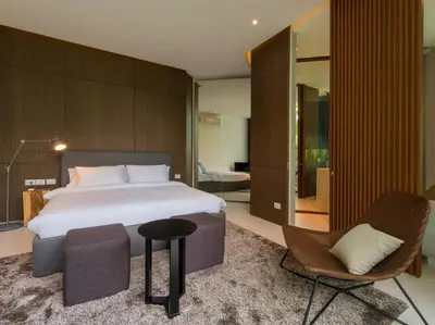a bedroom with a large bed and a chair at Villa Abiente in Thalang