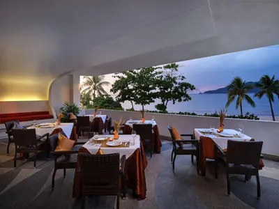 a restaurant with tables and chairs and a view of the ocean at Homm Bliss Southbeach Patong in Patong Beach