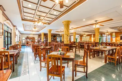 an empty restaurant with wooden tables and chairs at Tony Resort in Patong Beach