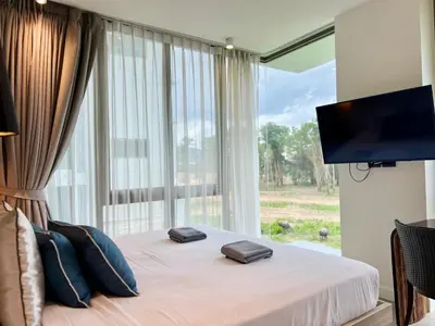 a bedroom with a bed with a large window at Oceanstone by RESAVA in Bang Tao Beach