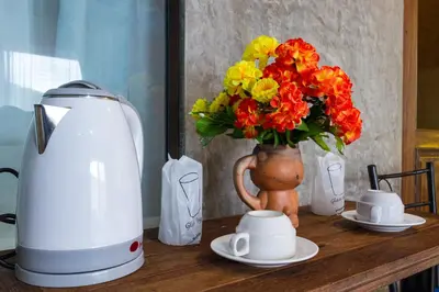 a table with a coffee maker and a vase with flowers at Kanya Cozy Bungalows Kata in Kata Beach