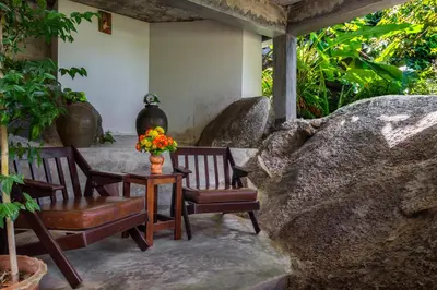 a patio with two chairs and a table with flowers on it at Kanya Cozy Bungalows Kata in Kata Beach