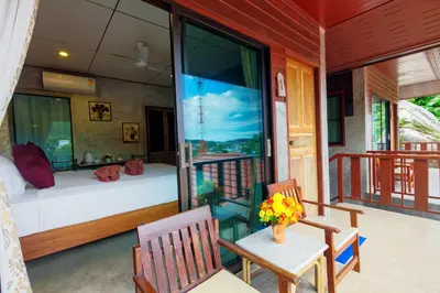 a room with a balcony with a bed and a table and chairs at Kanya Cozy Bungalows Kata in Kata Beach