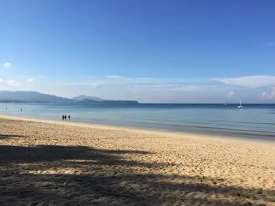 a group of people walking on the beach at KD Residence in Bang Tao Beach