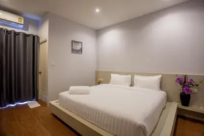 a bedroom with a large white bed with white pillows at Lin House in Thalang
