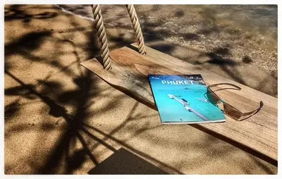 a book sitting on a swing in a park at 8IK88 Resort, Phuket - SHA Extra Plus in Por Bay
