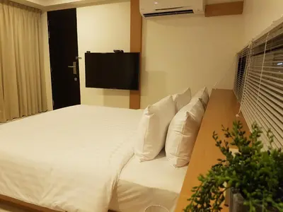 a bedroom with a white bed with a flat screen tv at 8IK88 Resort, Phuket - SHA Extra Plus in Por Bay