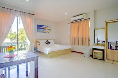 a bedroom with a bed and a desk and a window at Maikhao Beach Residence in Mai Khao Beach