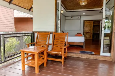 two chairs and a table on a porch with a bed at Sunrise House in Ko Yao Noi