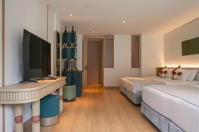 a hotel room with two beds and a desk at The Lantern Resorts Patong in Patong Beach