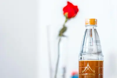a bottle of water with a flower in a vase at Airport Resort Phuket in Nai Yang Beach