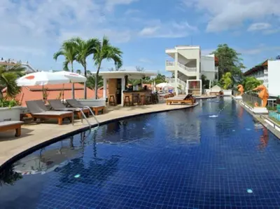 a swimming pool with chairs and umbrellas next to a building at Karon Princess Hotel SHA EXTRA Plus in Karon Beach