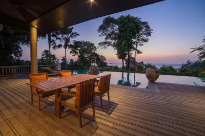 a wooden deck with a wooden table and chairs at Trisara Villas & Residences Phuket in Nai Thon Beach