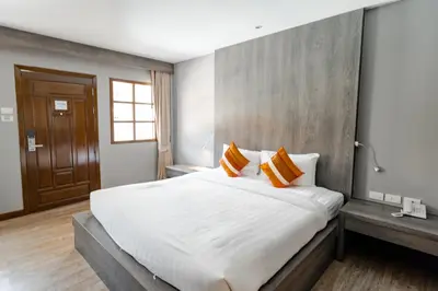 a bedroom with a large white bed with orange pillows at Naiya Buree Boutique Resort Nai Harn Beach in Rawai Beach