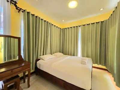 a bedroom with a bed and a dresser next to a window at Krabi Green Hill Pool Villas in Ban Nong Thale