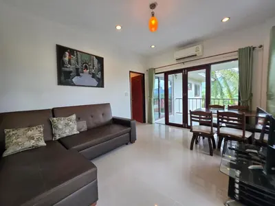 a living room with a couch and a dining room at Krabi Green Hill Pool Villas in Ban Nong Thale