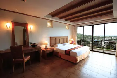 a bedroom with a bed and a desk and a balcony at Sun Hill Hotel Patong in Patong Beach